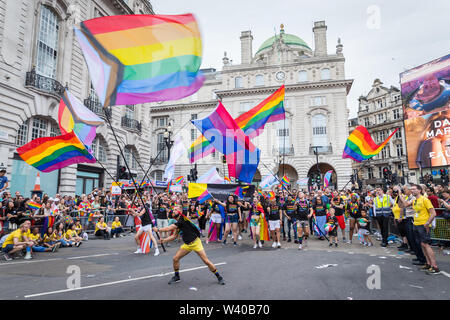 Festaioli gigante sventolando bandiere LGBT in Piccadilly Circus durante il Pride Parade Foto Stock