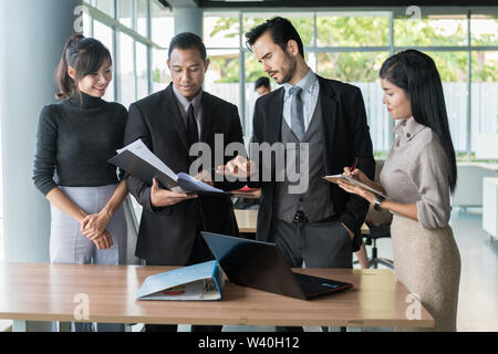 Smart manager spiegando riunione interna al suo team di progetto in un ufficio moderno. La multi etnico persona business group in tuta. Progetto e Business c Foto Stock