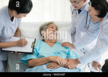 Asian team medico dei medici di esame e parlando di ASian donna anziana paziente, health care persone prendere nota su appunti in ospedale. Foto Stock