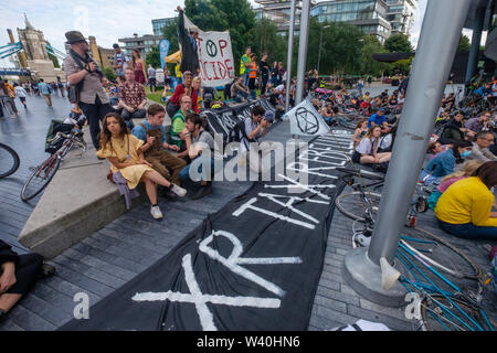 Londra, Regno Unito. Il 18 luglio 2019. Estinzione della ribellione sostenitori presso il municipio di rally e die-in per dichiarare uno sciopero fiscale contro la Greater London Authority, ritenuta il GLA elemento della loro tassa del consiglio fino a quando non abbandona i progetti che provoca il degrado ambientale e accelerare il collasso ecologico. Essi esigono il GLA arrestare tutti i progetti di infrastruttura di Londra inquinanti dell'aria e di investire in misure di riduzione delle emissioni di anidride carbonica e di promuovere stili di vita più sani e conferire un cittadino di assemblaggio di riscrivere il piano di Londra. Peter Marshall / Alamy Live News Foto Stock