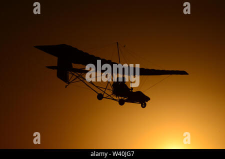 Velivolo ultraleggero al tramonto. Due persone volare basso con tranquillità Foto Stock