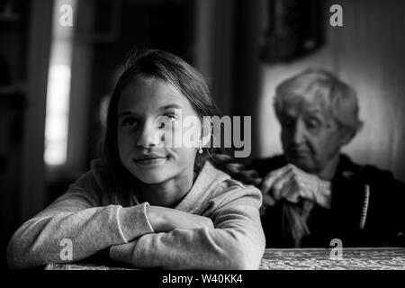 Una donna anziana trecce suo nipote di capelli. Bianco-nero in foto. Foto Stock