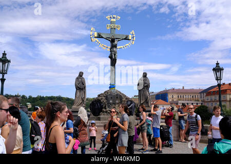 I turisti nella parte anteriore della statua della crocifissione sul Ponte Carlo a Praga, Repubblica Ceca Foto Stock