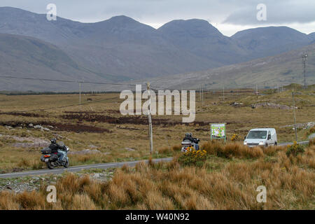 I turisti su due motociclette in Irlanda che viaggiano attraverso la terra della torbiera nella Contea di Galway sulla N59 verso Letterfrack in una giornata grigia nella parte ovest dell'Irlanda. Foto Stock