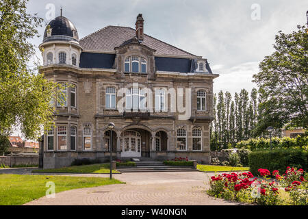 Knokke-Heist, Fiandre, Belgio - 18 Giugno 2019: Kursaalstraat. Storica grigio-marrone edificio di pescatori provinciale scuola, ormai defunta, nel suo parco Foto Stock