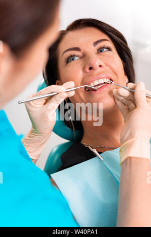 Mettere le bretelle dentali alla donna di denti in studio dentistico. Dentista esaminare paziente femmina con bretelle in studio dentistico. Close-up di un giovane Foto Stock