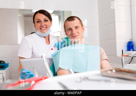 Ritratto di un dentista a discutere di un piano di trattamento di un paziente su un tablet Foto Stock