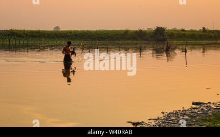 Mandalay, Myanmar - Feb 20, 2016. Un uomo locale per la cattura di pesce sul lago al tramonto a Mandalay, Myanmar (Birmania). Foto Stock