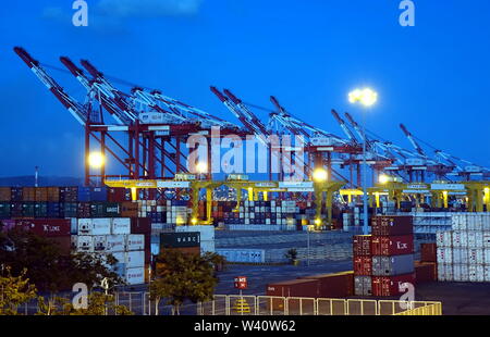 KAOHSIUNG, Taiwan -- Giugno 2, 2019: contenitori vengono caricati nel Porto di Kaohsiung all'imbrunire Foto Stock