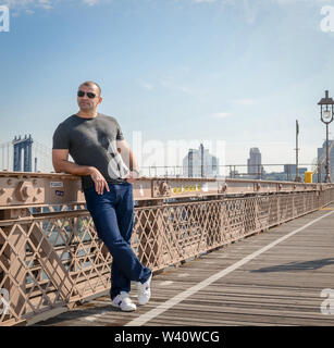 Giovane uomo che pongono sulla ringhiera ion il ponte di New York Foto Stock