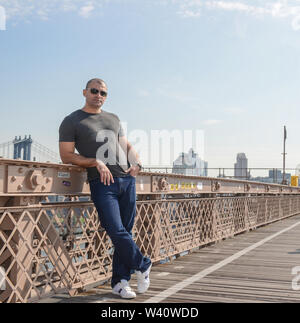 Giovane uomo che pongono sulla ringhiera ion il ponte di New York Foto Stock