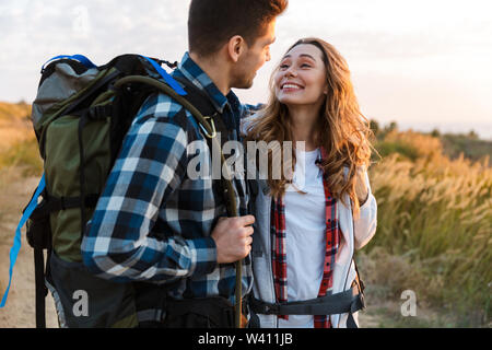 Allegro coppia giovane che trasportano Zaini Trekking insieme, camminando su un sentiero Foto Stock