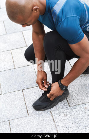 Close up di un africano sportsman legatura di lacci delle scarpe all'aperto Foto Stock