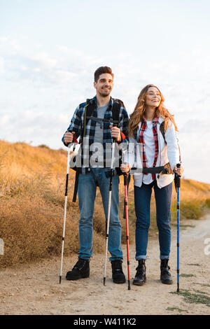Allegro coppia giovane che trasportano Zaini Trekking insieme, camminando su un sentiero Foto Stock