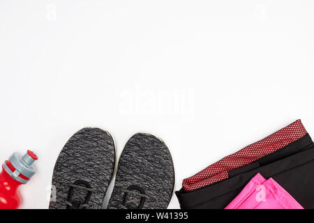 Tessuto nero scarpe e altri elementi per il fitness su uno sfondo bianco, vista dall'alto Foto Stock