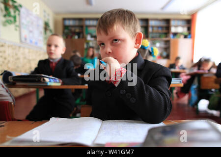 Un'Ucraino scolaro della scuola elementare a fare gli esercizi durante una lezione in classe. Radinka, Polesskiy distretto, Oblast di Kiev, Ucraina Foto Stock