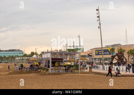 Barcellona, Spagna - 09 Novembre 2014: ristoranti e la gente sulla più famosa spiaggia di Barceloneta. Edificio moderno in background. Foto Stock