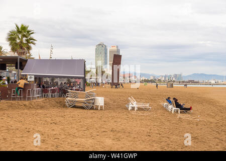 Barcellona, Spagna - 09 Novembre 2014: ristoranti e la gente sulla più famosa spiaggia di Barceloneta. Edificio moderno in background. Foto Stock