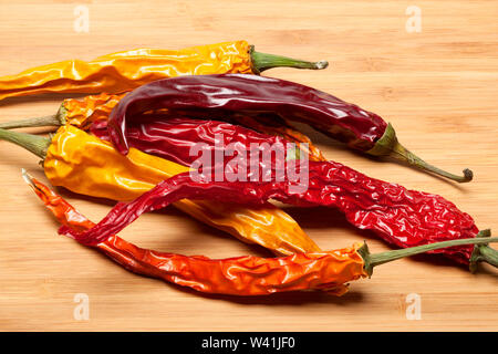 Peperoncino rosso secco in diversi colori su un sfondo di legno Foto Stock