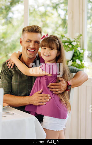 Il Daddy sorridente in senso ampio e abbraccia il suo grazioso figlia Foto Stock