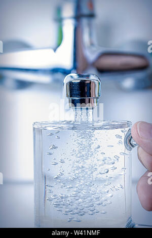 l'acqua scorre dal rubinetto della cucina nel bicchiere, primo piano. Foto Stock