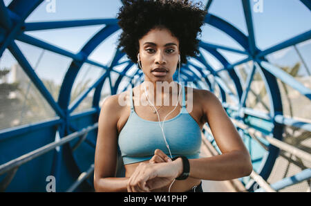 Giovane donna fitness con smart watch guardando la fotocamera. Sportive controllo impulso su smart watch app fitness. Foto Stock