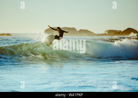 Giovane uomo acqua surf in mare. Surfista maschio nell'oceano acqua con tavola da surf. Foto Stock