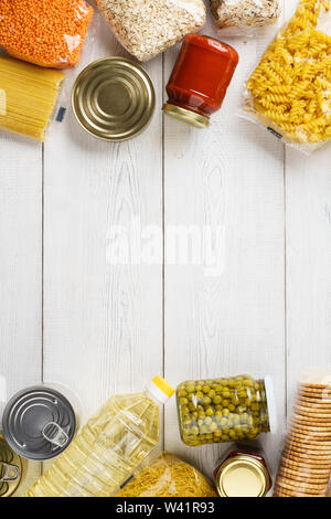 Vari cereali non cotte, grani, pasta e conserve alimentari su un bianco tavolo di legno. Ingredienti per la cottura. Telaio con sfondo spazio copia. Foto Stock