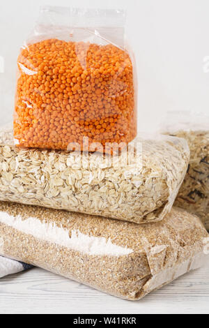 Vari cereali Semole in plastica trasparente sacchi su un tavolo da cucina. Beni alimentari. Riso, avena, lenticchia. Foto Stock