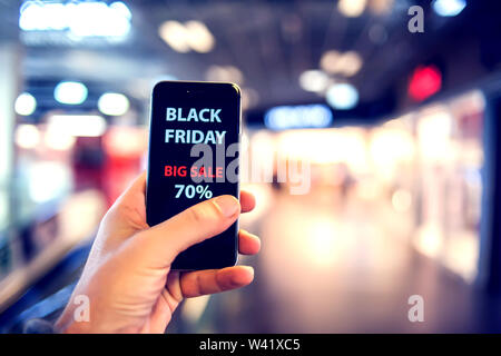 La gente, la vendita, il consumismo, il concetto di pubblicità - stretta di mano d'uomo azienda borse per lo shopping e lo smartphone con il black friday iscrizione presso il ma Foto Stock