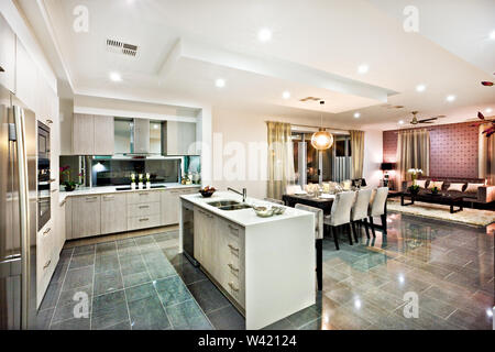 Moderno e brillante cucina con zona pranzo e soggiorno, compreso un bancone e stoviglie sulle piastrelle riflettente, vi sono luci lampeggianti a ni Foto Stock