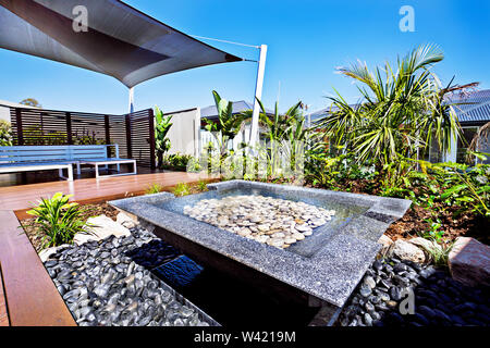 Casa moderna patio e stagno di acqua con un giardino riempite con ghiaia e piante verdi intorno alla zona residenziale Foto Stock