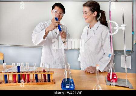 Gli studenti di medicina sorridente in un laboratorio e facendo alcuni esperimenti utilizzando bicchieri e tubi Foto Stock