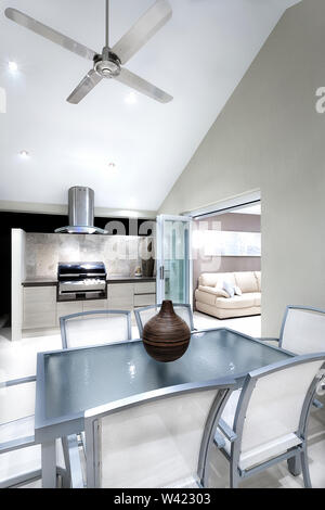 Moderna area da pranzo in vetro con sedie e tavoli in argento cornici accanto al grill a gas cabinet nel patio Foto Stock