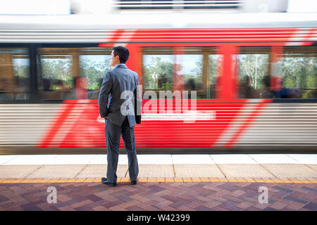 L'uomo con i file in attesa vicino stazione solare intorno alla zona, mattina il tempo e le ore di punta, il pavimento è piastrellato, sky è chiara. Foto Stock