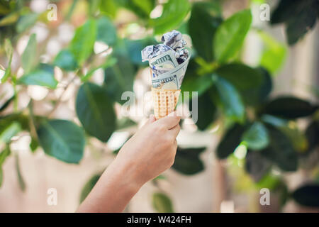 Wafer monetaria. le fatture del dollaro arrotolato nel cono gelato Foto Stock