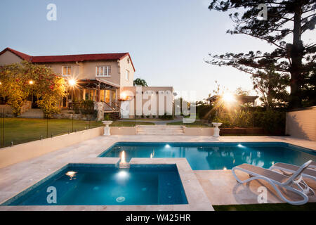 Moderna piscina area con luci da giardino di un palazzo, il Waterside è diviso in due parti e vi è una sedia per il relax, un alto albero può Foto Stock