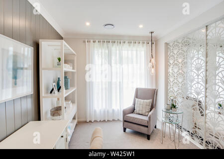 Elegante sedia alta in una piccola stanza con un tavolino e un show case rack, con un elegante muro designer. Foto Stock