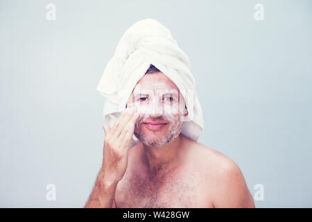 Un giovane uomo con crema idratante sul viso Foto Stock