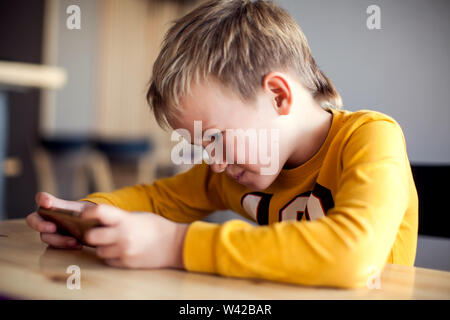 I bambini, la tecnologia e il concetto di internet. Poco sorridente ragazzo bambini giocare o navigare su internet su smartphone digitale Foto Stock