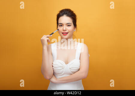 Vista ritagliata della donna asiatica con il trucco tenendo l'applicatore  mascara isolato su marrone, immagine stock Foto stock - Alamy