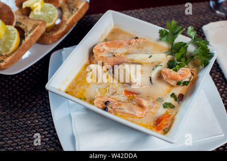 Frutti di mare minestra di crema con toast in piastra bianca sul tavolo. Foto Stock