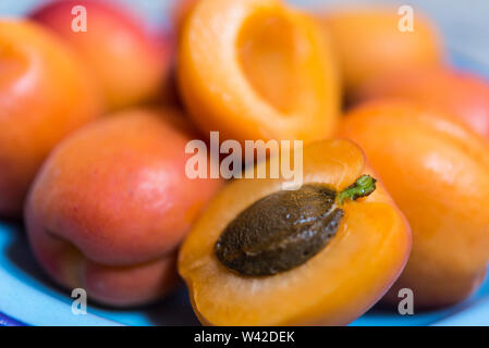 Intero e dimezzato fresche Albicocche con pietra in smalto blu a piastra Foto Stock