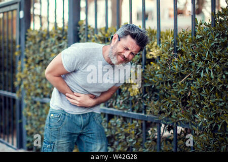 Uomo Forte sensazione stomachache sulla strada. La gente, la cura della salute e il concetto di medicina Foto Stock