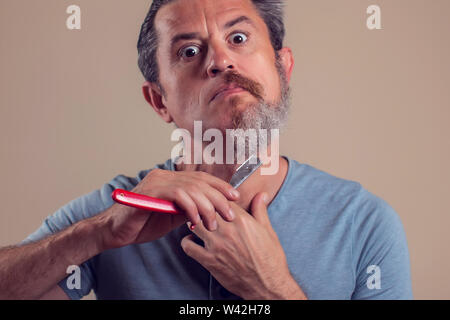 Un ritratto di uomo con la metà di barba e capelli su sfondo marrone Foto Stock