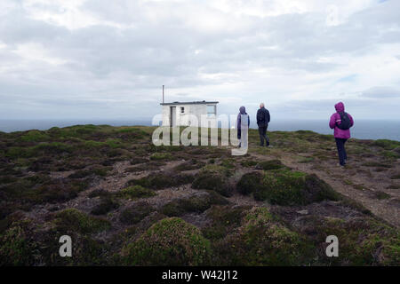 Tre persone che camminano su una traccia nella vecchia stazione di guardacoste belvedere sulla isola di Rathlin, County Antrim, Irlanda del Nord, Regno Unito. Foto Stock