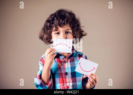 Kid boy selezionare tra positivo e negativo di espressioni. I bambini e le emozioni concetto Foto Stock