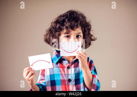 Kid boy selezionare tra positivo e negativo di espressioni. I bambini e le emozioni concetto Foto Stock