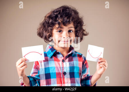 Kid boy selezionare tra positivo e negativo di espressioni. I bambini e le emozioni concetto Foto Stock