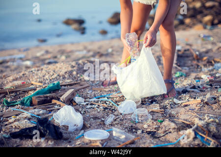 Donna raccogli garbage sulla spiaggia. La tutela ambientale concetto Foto Stock